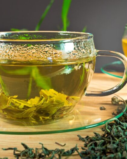 Clear glass teacup and sauce filled with loose-leaf green tea - learn about nutritional healing with Chinese Medicine with Goldsmith and Klein's book