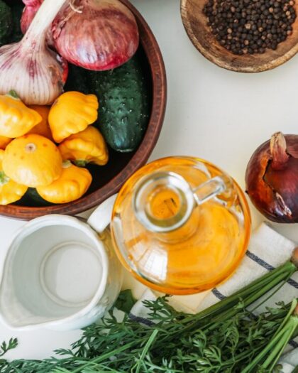 collection of fresh ingredients - pattypan squash, cucumber, garlic, olive oil, vinegar, red onion, carrots and peppercorns. Cook alongside traditional Chinese therapy methods and eat with the seasons using Nutritional Healing with Chinese Medicine from Robert Rose Books Inc.